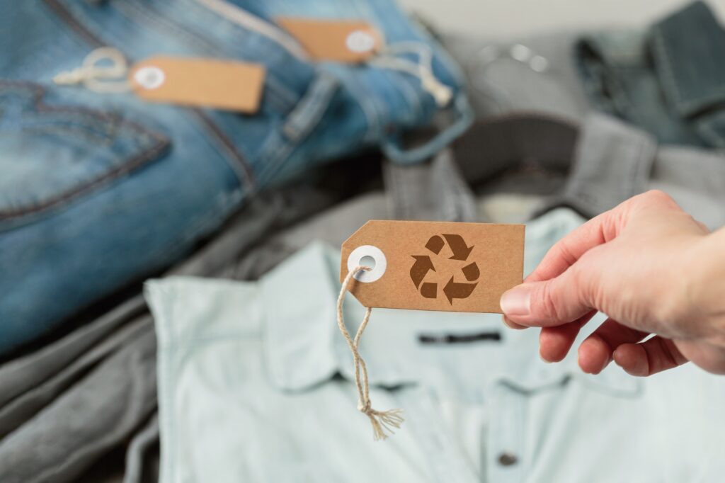 Womans hand holding craft paper tag with recycling symbol